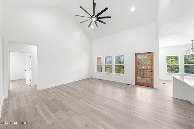 unfurnished living room featuring light wood finished floors, baseboards, high vaulted ceiling, and ceiling fan with notable chandelier