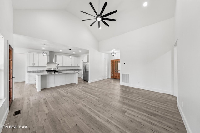 unfurnished living room with high vaulted ceiling, baseboards, visible vents, and light wood finished floors