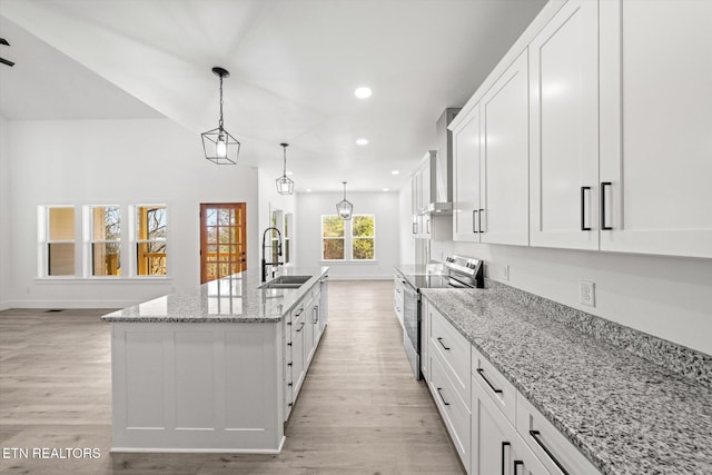 kitchen featuring stainless steel electric range oven, white cabinetry, light wood-style flooring, and a sink