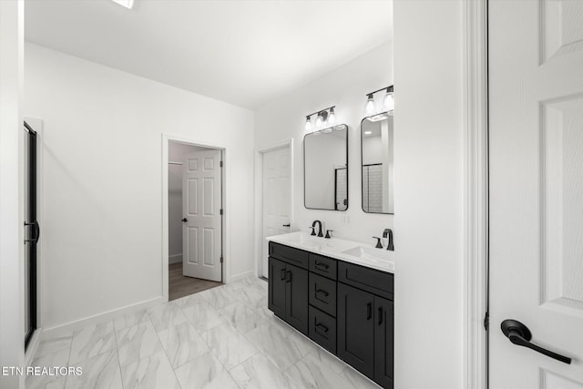 full bathroom featuring marble finish floor, double vanity, a sink, and baseboards
