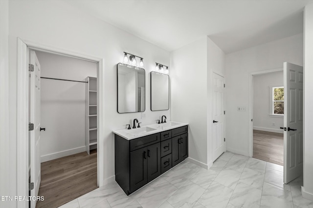 full bathroom with marble finish floor, a sink, and double vanity