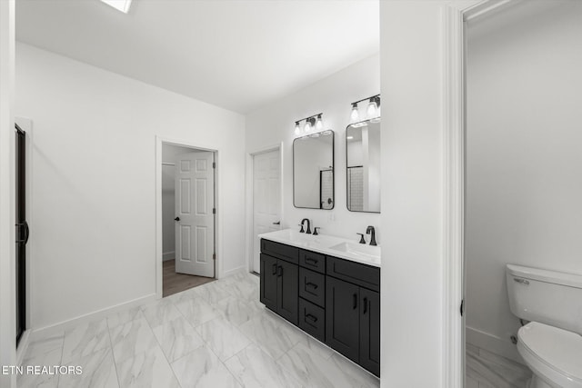 bathroom featuring toilet, marble finish floor, baseboards, and a sink