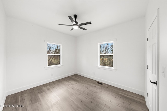 unfurnished bedroom featuring wood finished floors, visible vents, baseboards, and multiple windows