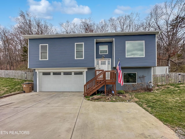 bi-level home with a front yard, fence, driveway, and an attached garage