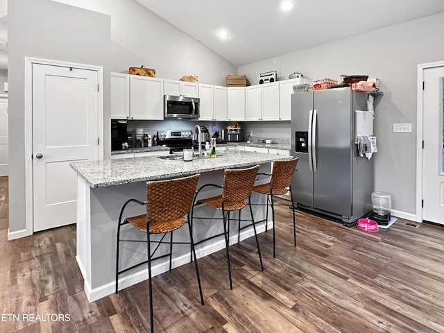 kitchen with appliances with stainless steel finishes, dark wood-type flooring, white cabinetry, a sink, and an island with sink