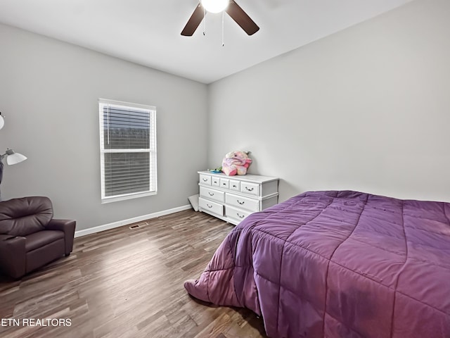 bedroom featuring ceiling fan, wood finished floors, visible vents, and baseboards