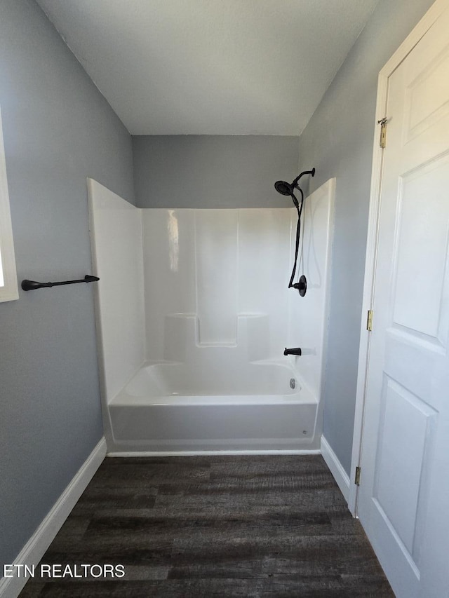 full bath featuring shower / bathtub combination, wood finished floors, and baseboards