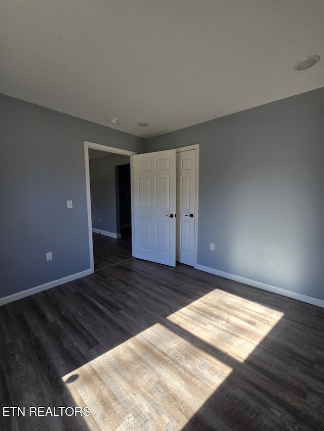 unfurnished bedroom featuring dark wood-style floors and baseboards