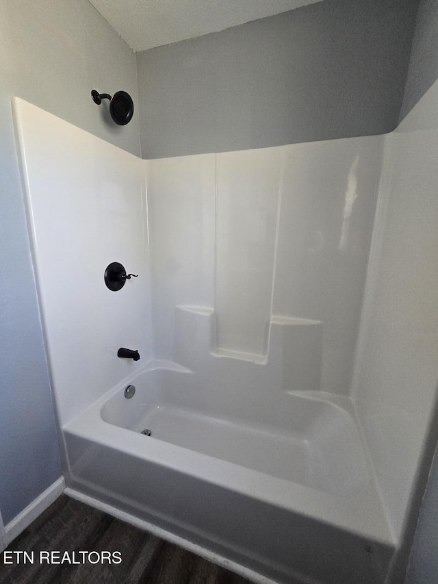 bathroom featuring shower / bathing tub combination, baseboards, and wood finished floors