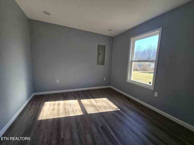 unfurnished room featuring wood finished floors, electric panel, and baseboards