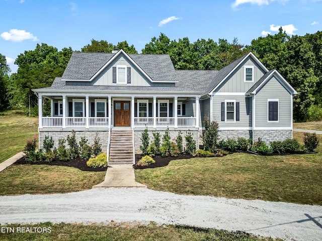 view of front facade featuring covered porch, a shingled roof, board and batten siding, and a front yard