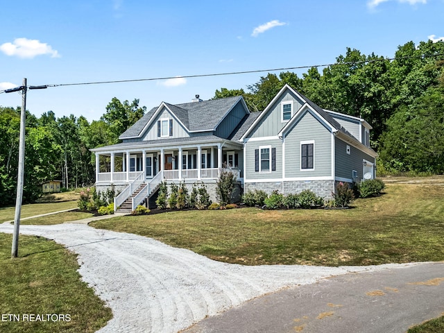 view of front facade with covered porch, board and batten siding, stone siding, driveway, and a front lawn