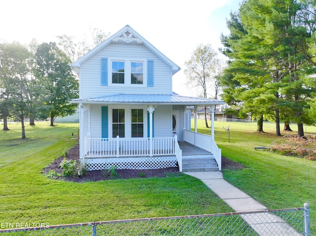 view of front of property with covered porch, fence, metal roof, and a front yard