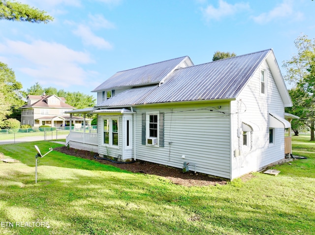 back of house with metal roof and a yard