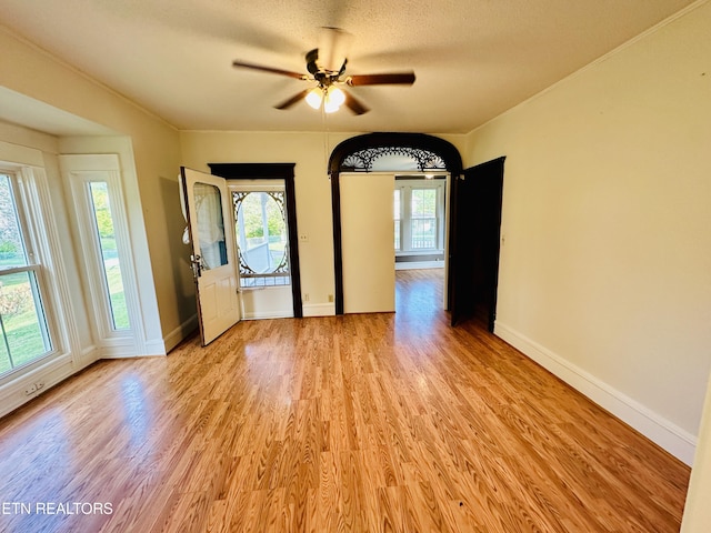 unfurnished room featuring a textured ceiling, a ceiling fan, light wood-style flooring, and baseboards