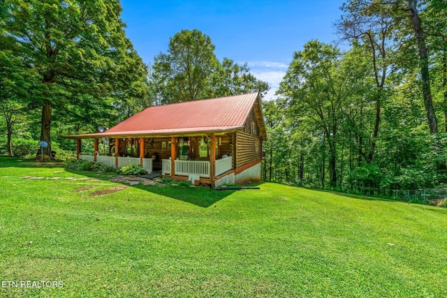 view of front of home featuring a front yard, covered porch, metal roof, and log siding