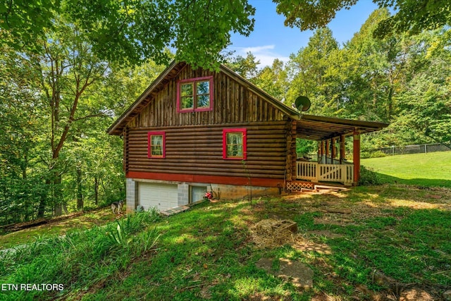 view of home's exterior with a yard, log exterior, and fence