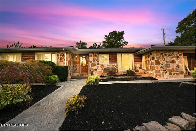 ranch-style house with stone siding and aphalt driveway