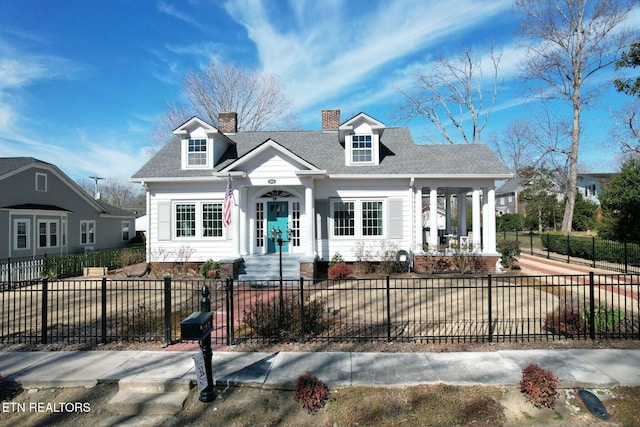 cape cod house featuring roof with shingles, a fenced front yard, and a chimney