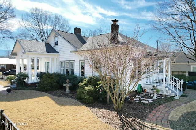 back of property featuring a shingled roof and a chimney