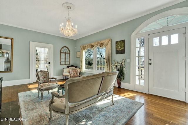 interior space with a chandelier, ornamental molding, baseboards, and wood finished floors