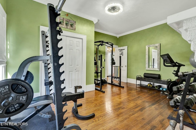 exercise area featuring baseboards, ornamental molding, and wood finished floors