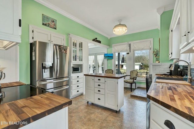 kitchen featuring wood counters, ornamental molding, white cabinetry, stainless steel refrigerator with ice dispenser, and a sink