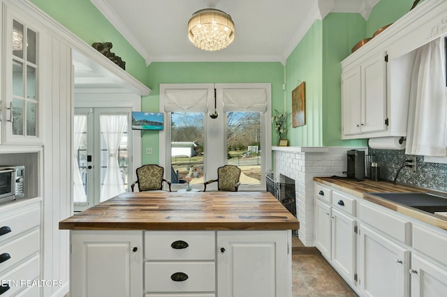 kitchen featuring white cabinets, ornamental molding, and wooden counters