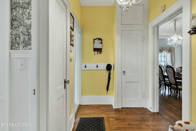 hallway featuring dark wood-style floors and an inviting chandelier