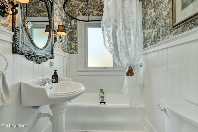 full bathroom featuring toilet, a wainscoted wall, and wallpapered walls