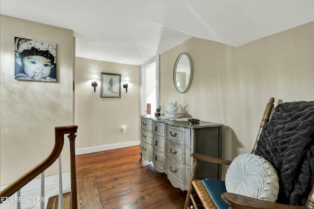 sitting room featuring dark wood-style floors, an upstairs landing, and baseboards