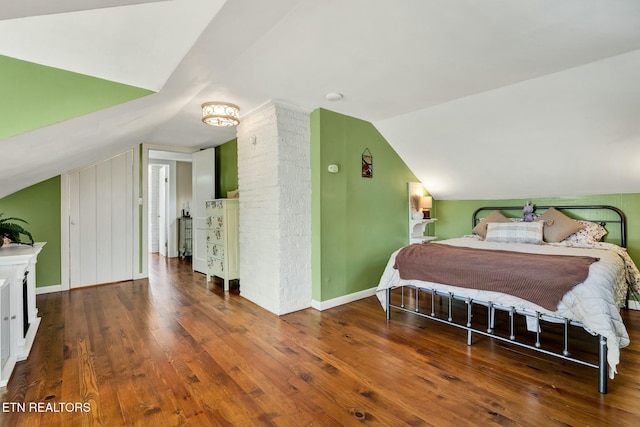 bedroom with vaulted ceiling, wood-type flooring, and baseboards