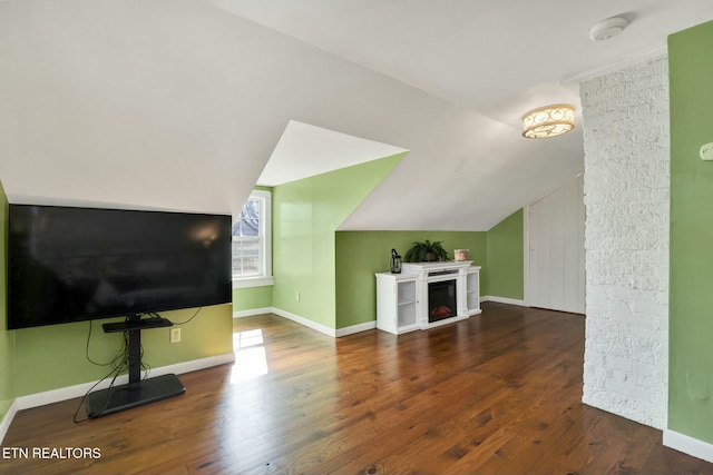 unfurnished living room with lofted ceiling, wood finished floors, and baseboards