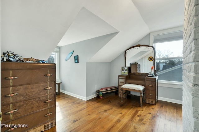 living area featuring lofted ceiling, wood-type flooring, and baseboards