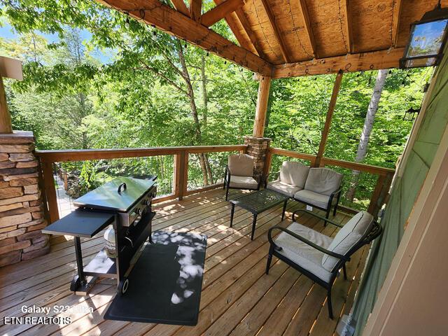 wooden terrace featuring area for grilling and an outdoor hangout area