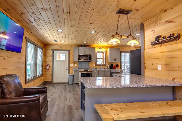 kitchen featuring light wood-style flooring, gray cabinetry, wood walls, wood ceiling, and appliances with stainless steel finishes