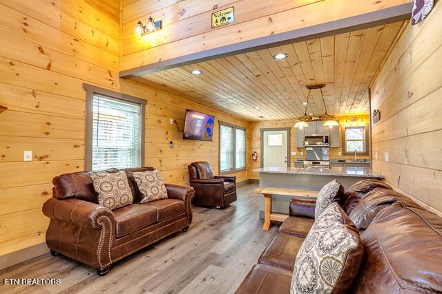 living area featuring wooden walls, wooden ceiling, wood finished floors, and a healthy amount of sunlight