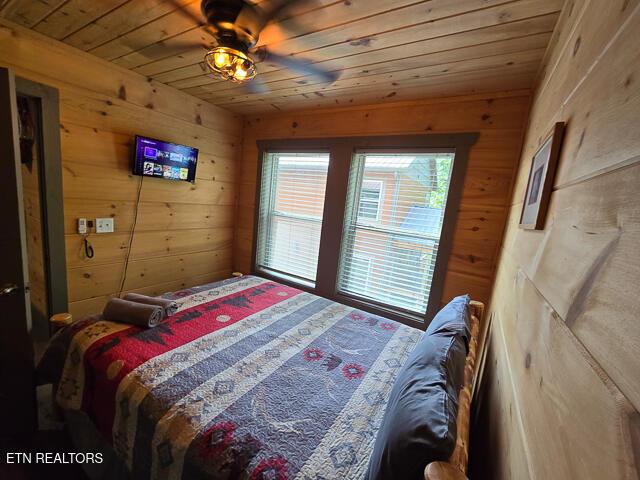 bedroom with wood walls, wooden ceiling, and a ceiling fan