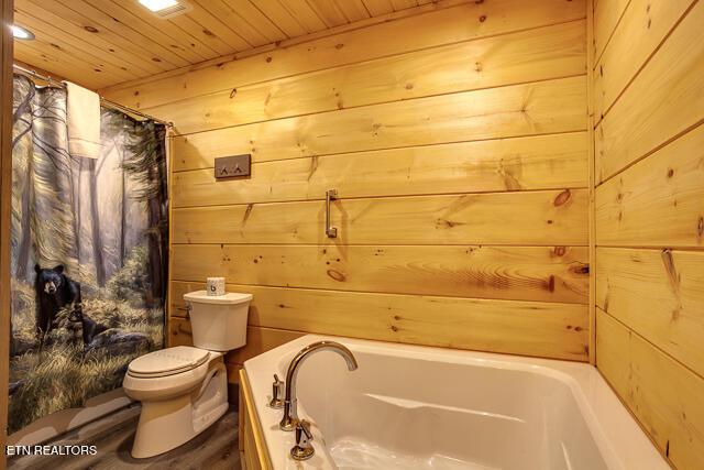 full bath with a tub, wooden ceiling, wooden walls, and toilet