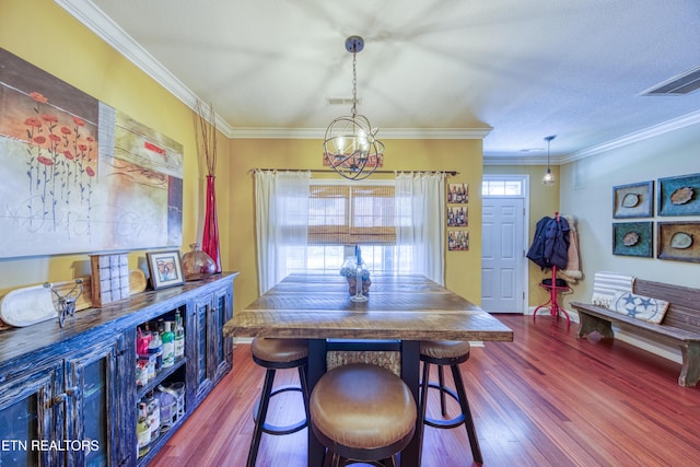 dining space featuring dark wood-type flooring, visible vents, and crown molding