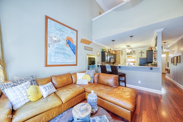 living room featuring a towering ceiling, crown molding, baseboards, and dark wood-type flooring