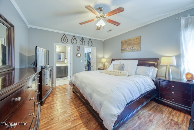 bedroom with ensuite bathroom, light wood-style flooring, a closet, a walk in closet, and crown molding