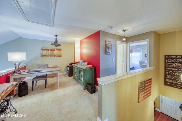 interior space featuring vaulted ceiling, attic access, and baseboards