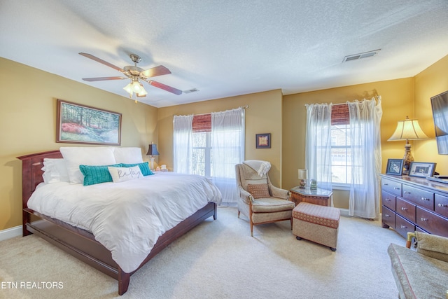 bedroom featuring light colored carpet, visible vents, and a textured ceiling