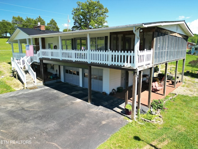 view of front of house with a porch, an attached garage, metal roof, a front lawn, and stairs