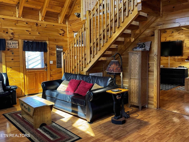 living room with wooden walls, wood finished floors, wood ceiling, stairs, and beam ceiling