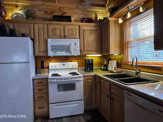 kitchen featuring white appliances, light countertops, a sink, and wood walls