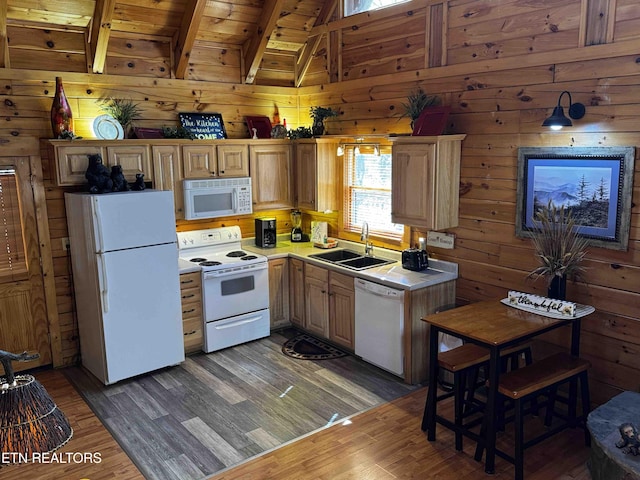 kitchen with white appliances, wood finished floors, a sink, and wood walls