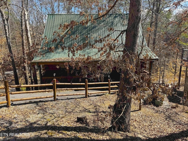 rustic home featuring metal roof and fence