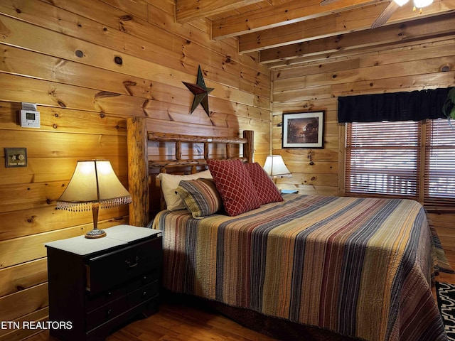 bedroom with wood walls, beam ceiling, and wood finished floors